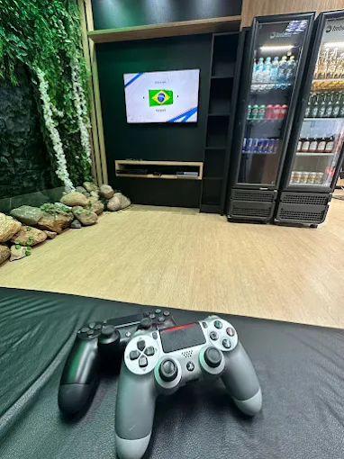 Área de espera da Barbearia Joinville com TV, videogame e geladeira de bebidas